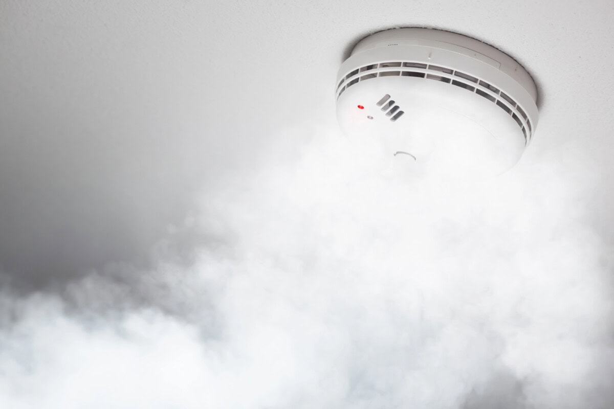 Smoke detector of fire alarm in action, white background