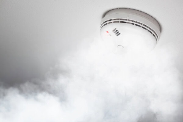 Smoke detector of fire alarm in action, white background